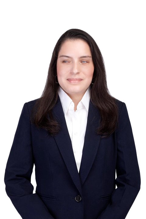 Priscilla Garces, con una leve sonrisa, con chaqueta azul marino sobre camisa blanca, fotografiada sobre fondo blanco.