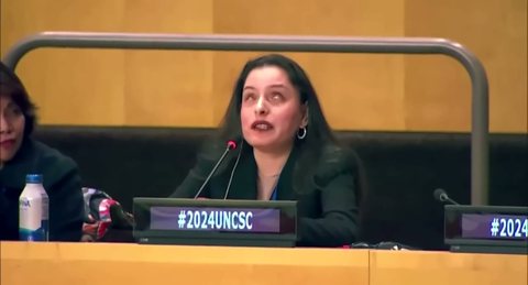 Priscilla Garces habla ante un micrófono en una mesa de conferencia con el rótulo #2024UNCSC.